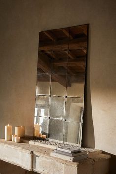 a mirror sitting on top of a table next to candles and a candle holder in front of it