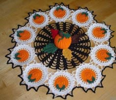 a crocheted doily with an orange and black turkey on it sitting on a wooden floor