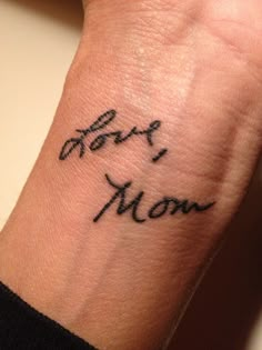 a woman's wrist tattoo with the word mom written on her left arm and in cursive writing