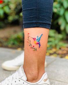 a woman's foot with a humming bird tattoo on her left side calfocks