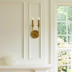 a white fireplace with two gold sconces on it