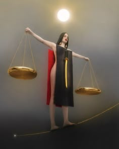 a woman in a black dress holding two gold scales