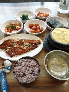 a wooden table topped with plates and bowls filled with different types of food on top of it