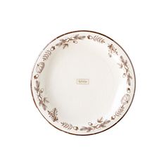 an empty white plate with gold trimmings and leaves on the rim, against a white background