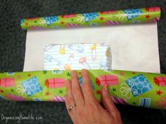 a hand is opening a wrapped gift box with wrapping paper on the bottom and inside