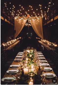 a long table is set with candles, plates and napkins for an elegant dinner