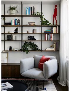 a living room filled with furniture and bookshelves next to a wall mounted book shelf