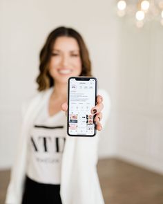 a woman holding up a cell phone in front of her face and smiling at the camera