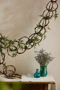 a sculpture made out of branches and flowers on a table next to a blue vase