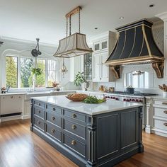 a large kitchen with an island in the middle and two pendant lights hanging from the ceiling