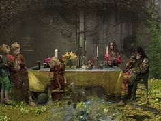 a group of people sitting around a table with candles and flowers on top of it