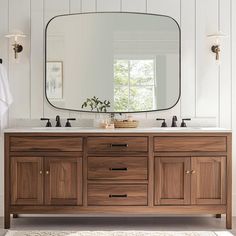 a bathroom vanity with two sinks and a large mirror over the top that hangs above it