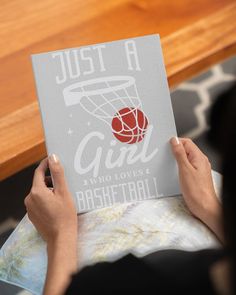 a person holding up a book that says just a girl who loves basketball on it