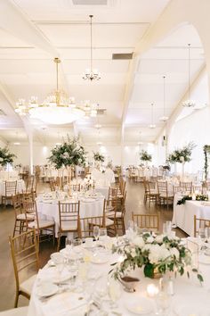 the tables are set with white linens and greenery for an elegant wedding reception