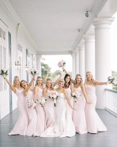 a group of bridesmaids in pink dresses posing for a photo on the porch