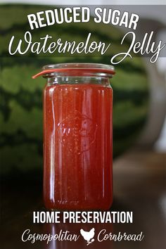 a jar filled with watermelon jelly sitting on top of a table next to a cucumber