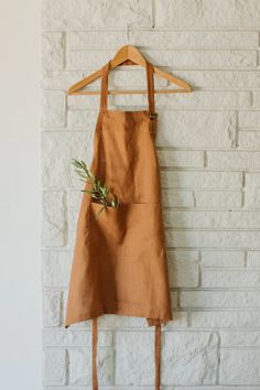 a brown apron hanging on a white brick wall