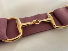 a close up of a gold buckle on a pink strap