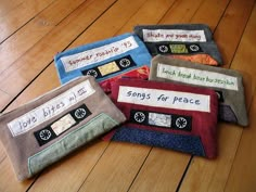 four small zippered pouches with words written on them sitting on a wooden floor