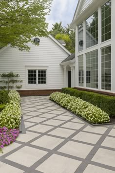 a large white house with many windows and plants in the front garden area on either side