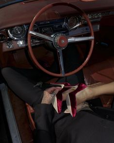 a man sitting in the driver's seat of a car with his feet on the steering wheel