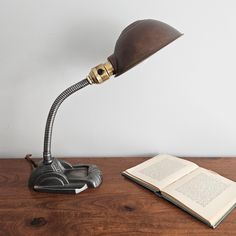 a lamp that is on top of a table next to an open book and a phone