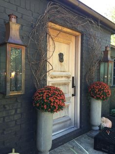 two large planters with orange flowers are in front of the door to a house