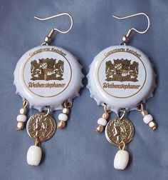 two white bottle caps with gold and white beads are hanging from earwires on a blue background