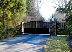 a gated driveway leading into a wooded area