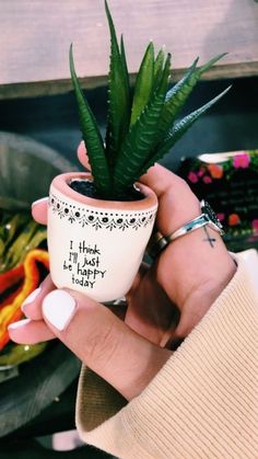 a person holding a potted plant with writing on it