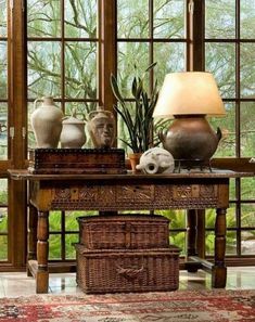 a table with two vases and a basket on it in front of a window