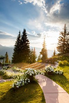 an outdoor ceremony set up with flowers and greenery in the foreground at sunset