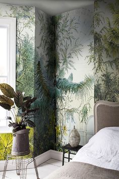 a bedroom with wallpaper and plants on the walls next to a bed in front of a window