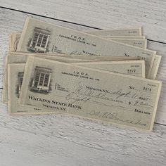 three old bank notes sitting on top of a white wooden table next to each other