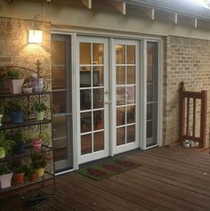 a patio with two doors and potted plants on the side walk way to an outdoor living area