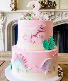 a pink and white cake with dinosaurs on it