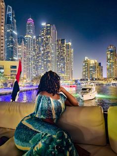 a woman sitting on top of a couch in front of a city skyline at night