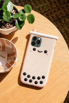 a phone case sitting on top of a wooden table next to a potted plant