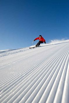 a man riding skis down the side of a snow covered slope in front of a blue sky