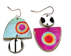 two colorful earrings hanging from hooks on a white background, one with an abstract design and the other with circles