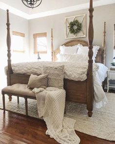 a large bed sitting on top of a wooden floor next to a white rug and window