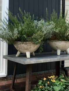 two cement planters sitting on top of a table next to each other in front of a house