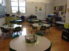 an empty classroom with tables and green chairs