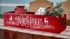 a red wooden box with christmas decorations in it on a dining room table and chairs