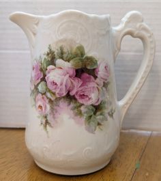 a white pitcher with pink roses painted on it