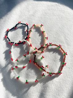 three bracelets are laying on top of the snow covered ground, each with different colored beads