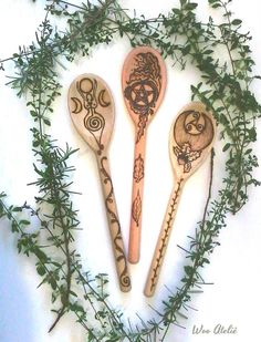 three wooden spoons sitting next to each other on top of green leaves and branches