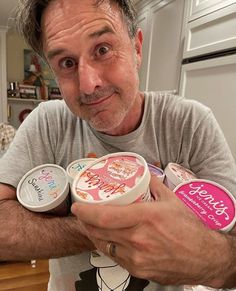 a man holding two containers of yogurt in his hands and looking at the camera