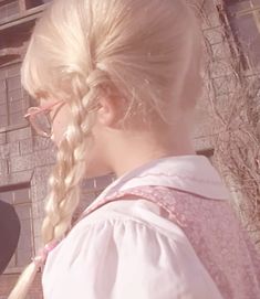 a woman with blonde hair and glasses standing in front of a brick building