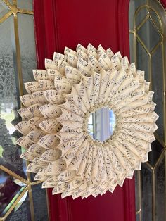 a wreath made out of sheet music sits in front of a red door